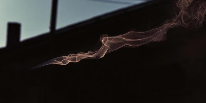 A wispy smoke trail against a dark, architectural silhouette creates an ethereal image. photo