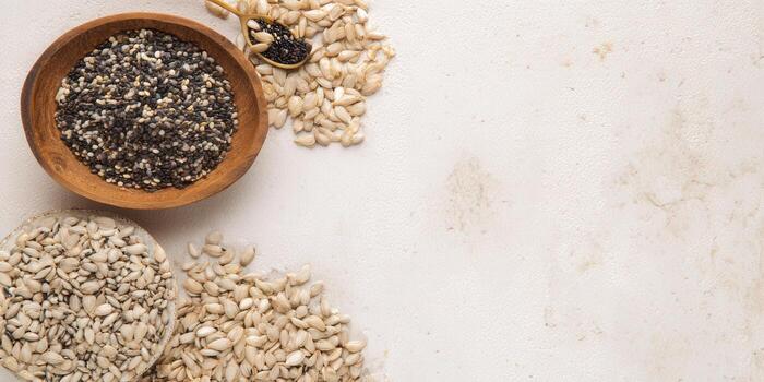 chia semillas y girasol semillas son desplegado en de madera bochas y un cuchara en un texturizado blanco superficie. foto