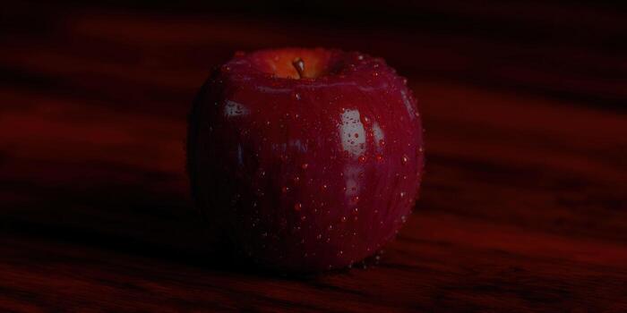 A close-up of a vibrant, red apple covered in water droplets on a wooden surface. photo