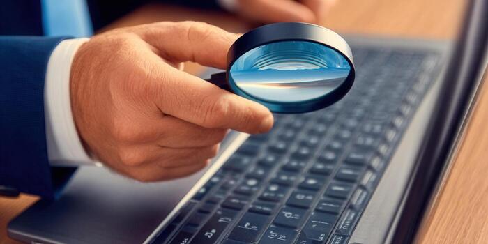 A close-up shot of a hand using a magnifying glass to examine a laptop keyboard. photo