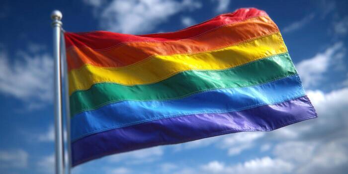 Rainbow flag waving in the wind, representing pride and equality in a bright sky. photo