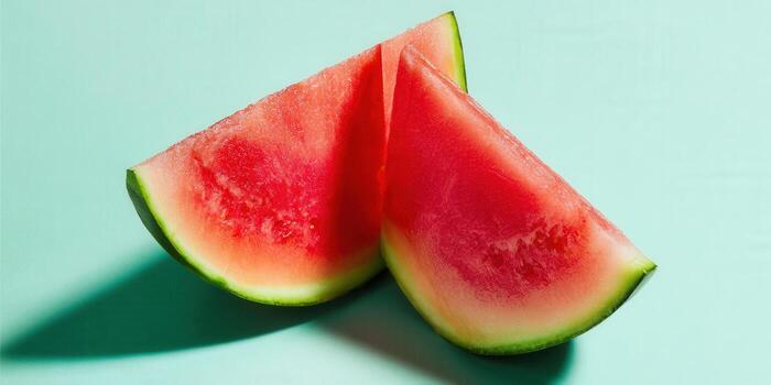 Refreshing watermelon slices sit side-by-side on a solid teal background, perfect for summer. photo