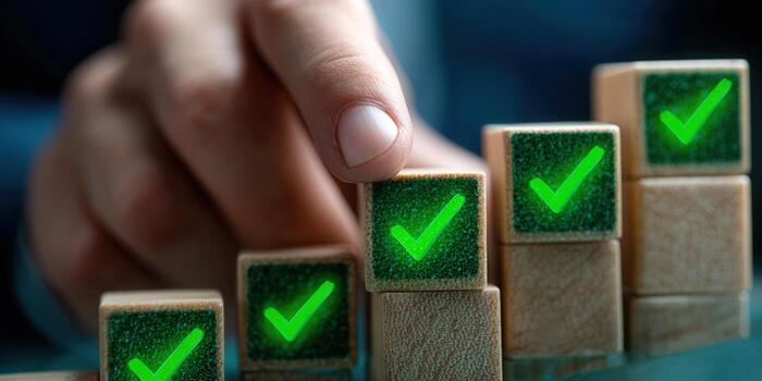 A hand completing a stack of blocks, each with a green checkmark, symbolizing success and achievement. photo