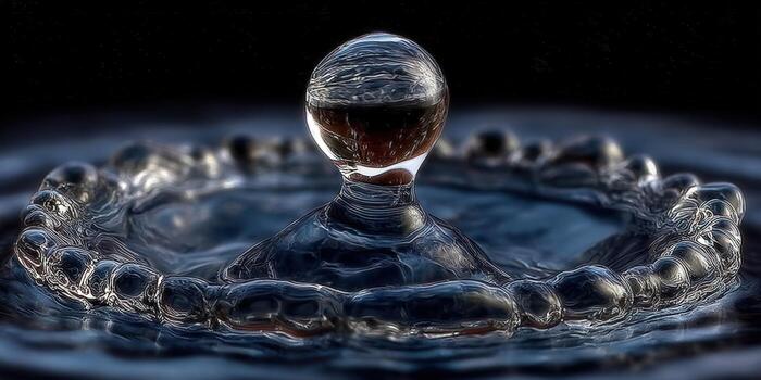Close-up shot of a water droplet forming a crown and intricate ripples. photo