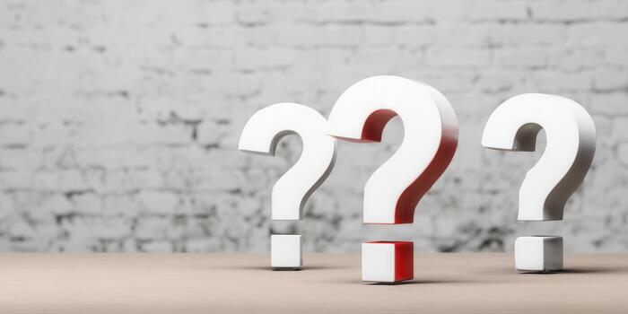 Three white question marks with a red accent stand on a wooden table. photo