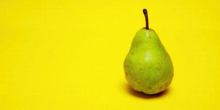 A ripe green pear is isolated against a bright yellow background, ready to be enjoyed. photo