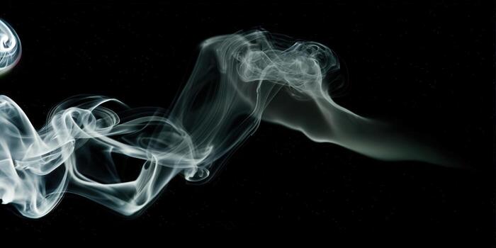 Delicate white smoke gracefully swirls on a black backdrop, creating an ethereal and artistic display. photo