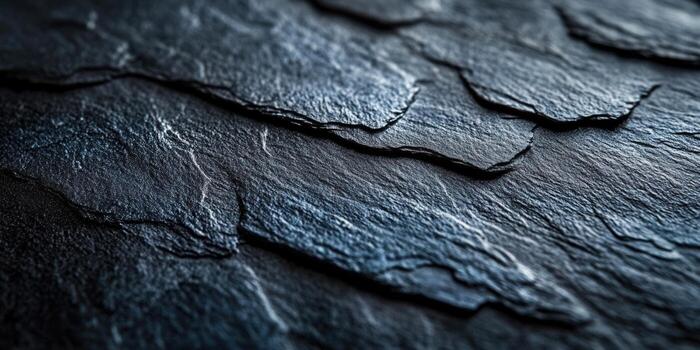 A detailed view of dark, textured slate roof tiles creates an interesting pattern. photo