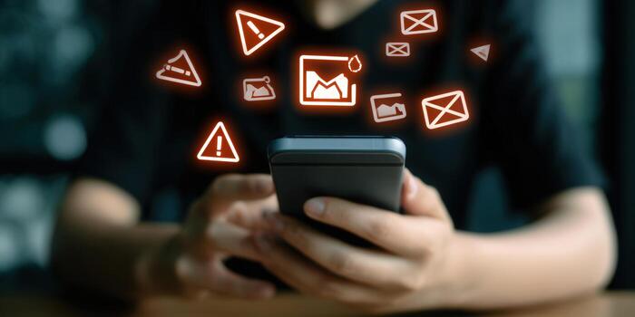 Close-up of a person using a smartphone, with digital warning icons floating around the phone photo