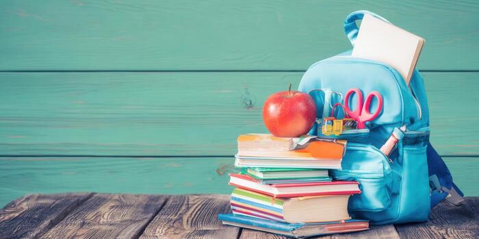 A vibrant image featuring a backpack with school essentials and an apple on a wooden desk photo