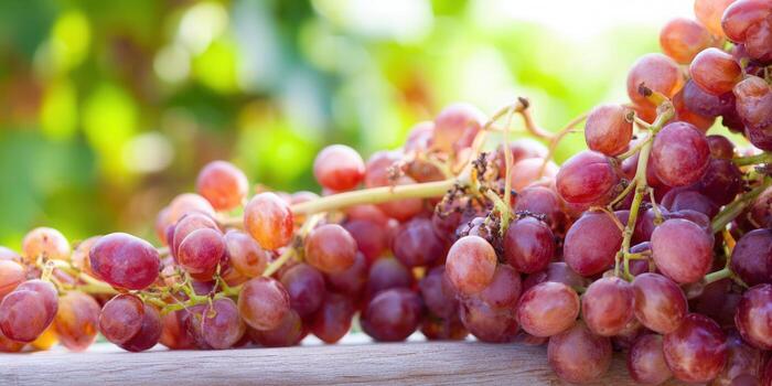 A cluster of juicy, ripe red grapes on a wooden surface with a soft bokeh background. photo