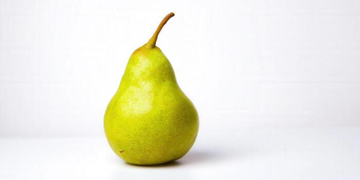 A single, perfectly ripe green pear stands out against a clean white backdrop, ready to be enjoyed. photo