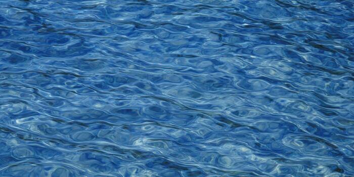 A mesmerizing shot of water's surface, displaying beautiful, smooth waves and vibrant blue hues. photo