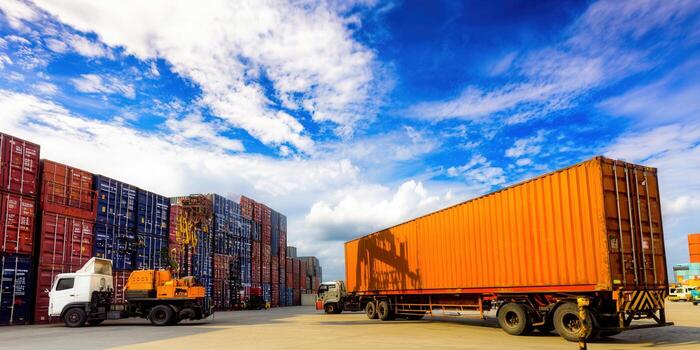 Shipping containers stacked high with a truck on a sunny day, ready for global delivery. photo