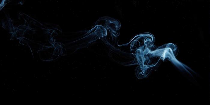 Elegant wisps of blue smoke dance across a stark black backdrop, creating a captivating visual photo