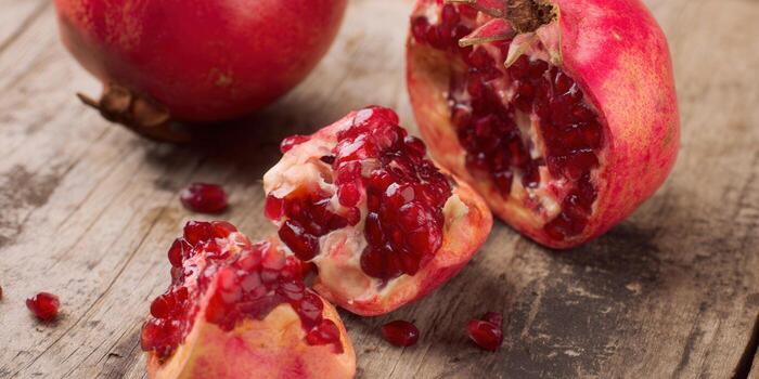 Close-up of a vibrant, opened pomegranate, showcasing its juicy, ruby-red seeds on a wooden surface. photo