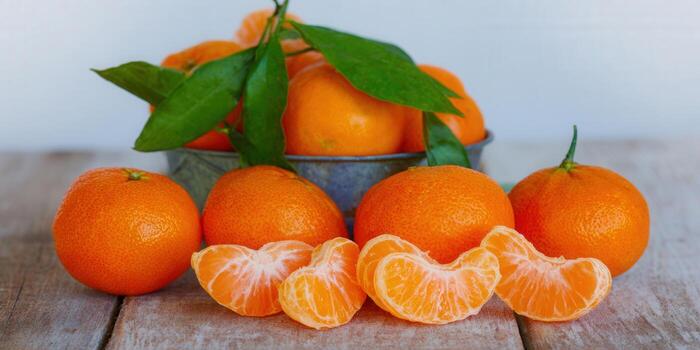 Bright tangerines, some segmented, on a wooden table, showcasing freshness and natural appeal. photo
