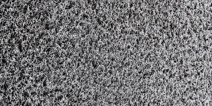 A detailed close-up of a textured doormat featuring a repetitive, abstract pattern in grayscale. photo