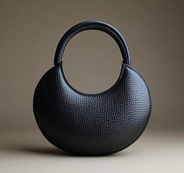 A black purse with a round shape on a surface photo