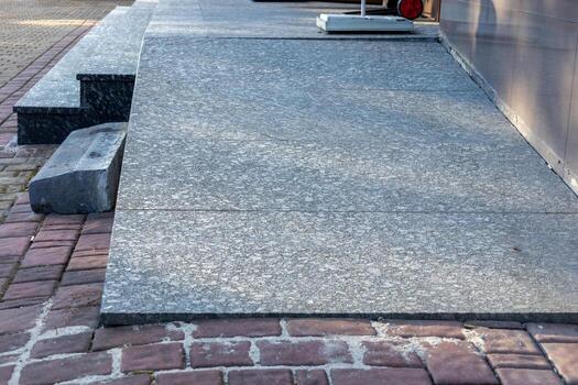 The view features a smooth gray stone sidewalk next to textured brick pavement, creating a contrast in surface design photo