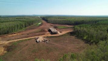 Aerial drone view of highway construction site with unfinished bridge, machinery, and forest landscape. video