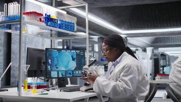 svart kvinna expert- analyserar prover i kemi labb med mikroskop och observation verktyg. forskare framåt genetik forskning, patologi analys med biokemi studier. kamera a. video