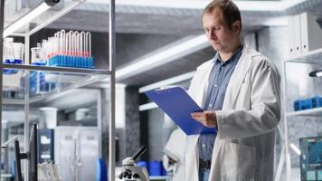 manlig vetenskaplig expert- granskning prover i hög tech laboratorium miljö, medicinsk upptäckt bearbeta innebär bioteknik forskning och molekyl vetenskap. sjukvård data innovation. kamera b. video
