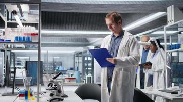 Portrait of smiling scientific expert making notes on clipboard files in biolab, working in biochemistry and genetics research. Professional engineer studying discovery. Camera A. video