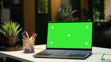 Laptop with an isolated chroma key display placed on office desk, late night work at the company. Empty boardroom space with reports and projections, ready for development. video