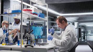 manlig forskare handtag pipett med liten droppe över burk under procedur i de labb. blandning förberedelse stödjande genetik forskning, nanoteknologi och lösningar genom analytisk metoder. kamera a. video