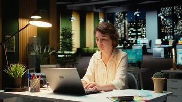 kvinna assistent engagerande i en telefon ring upp efter timmar på de kontor, ger insikt på finansiell data rapporter och Övrig metrik för bokföring. chattar på en smartphone förbindelse. kamera a. video