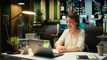 professionale donna si siede nel davanti di il computer portatile durante un' Teleconferenza, impegnato nel digitale discussione. interagendo con partecipanti, dimostrando adattabilità nel networking sessione. telecamera un. video
