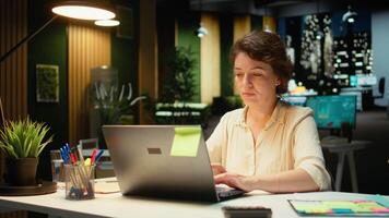 empleado comprometido en investigando y documentando números para reporte actualizaciones para negocio empresa, noche hora trabajo en un oscuro oficina. enfoque en objetivos y proyecto desarrollo. cámara una. video