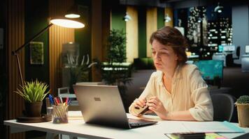 Executive manager reflecting on a tactical decision and playing with stapler, works after hours. Woman engaging in critical thinking, evaluating options for different perspective. Camera A. video