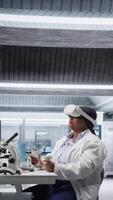 verticale nero donna utilizzando vr cuffia per Esplorare 3d interattivo sperimentare nel laboratorio, biochimica e nanotecnologie studia. esperto usi virtuale la realtà bicchieri e gadget per scienza. telecamera b. video