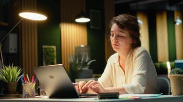 Businesswoman wondering about possible solutions to a dilemma with laptop at desk, intense concentration to evaluate options with both logical deduction and intuitive observation. Camera B. video