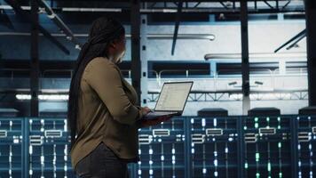 Software sviluppatore nel dati centro utilizzando il computer portatile per coordinata distribuzione di nuovo server architettura. server centro esso professionale utilizzando taccuino per fare srotolare di sicurezza informatica struttura, telecamera B video