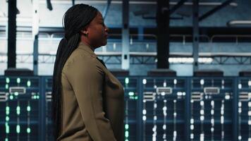 systemet administratör arbetssätt i data Centrum till optimera nätverk infrastruktur. afrikansk amerikan kvinna i i server bruka diagnos och lösa hårdvara felfunktioner använder sig av enhet video