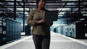 supervisore nel dati centro utilizzando il computer portatile per coordinata distribuzione di nuovo server architettura. server azienda agricola esso specialista utilizzando taccuino per fare srotolare di sicurezza informatica struttura, proteggere dati, telecamera un' video