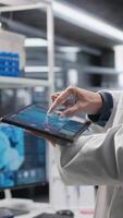 Vertical Close up of tablet running important experiment data in a research lab, man scientist studies experiment. Biotechnology, genetics research and pharmacology for progress in chemistry. Camera A. video