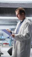 Vertical Male scientific expert reviewing samples in high tech laboratory setting, medical discovery process involves biotechnology research and molecular science. Healthcare data innovation. Camera A. video