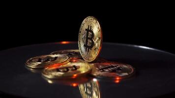 en bitcoin står atop en stack av Övrig mynt, roterande mot en svart bakgrund. bitcoin spinning på en spegel yta, skapande reflektioner under dem. video