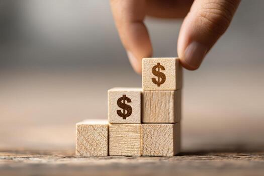 Hand stacking wooden blocks with dollar signs, symbolizing financial growth photo