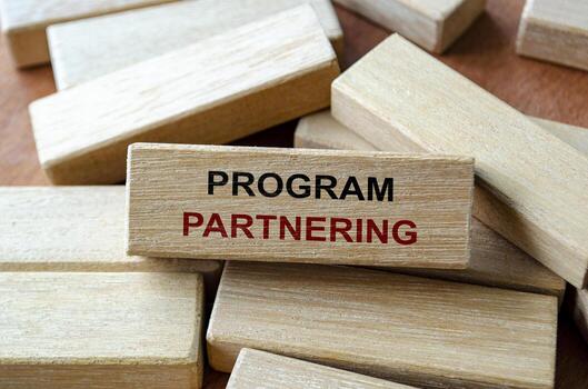 Program partnering text written on wooden blocks highlighting collaboration within projects and initiatives. photo