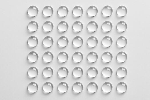 Light grey matte background with a neat uniform grid of glossy rounded droplets. photo