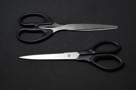 Two stationery scissors ready for action on a deep black backdrop. This photo symbolizes creativity, DIY projects, crafting, and the start of a new endeavor.