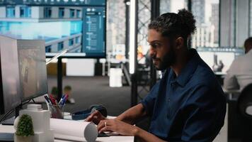 Middle eastern engineer finalizing interior design plans for a building in office, working toward residential project layout and structure on dual monitors computer. City planning. Camera B. video