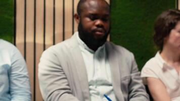 tre jobb sökande väntar i de hall med dokument och återupptar, framställning för en formell intervju med de hr team. sökande få otålig i de kö på de korridor. kamera b. video