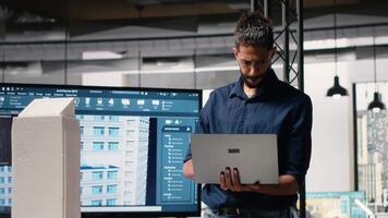 manlig utvecklare utvärdera arkitektonisk 3d modeller och planer till hitta mätningar och zonindelning föreskrifter, samlar konstruktion webbplats och layout detaljer i de kontor. kamera b. video