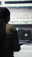 Vertical Engineer in server hub using laptop to upgrade rigs for increase in workload capacity using AI deep learning. Data center employee uses artificial intelligence to improve processing speed, camera A video